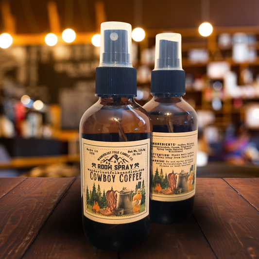 Two bottles of 'Rodeo Spray Cowboy Coffee' on a wooden table with a blurred bar background.